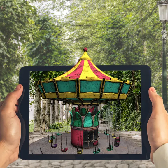 Bildbeispiel für Augmented Reality mit einem gehaltenen iPad wo das Prinzip des AR durch ein Karusell verständlich wird