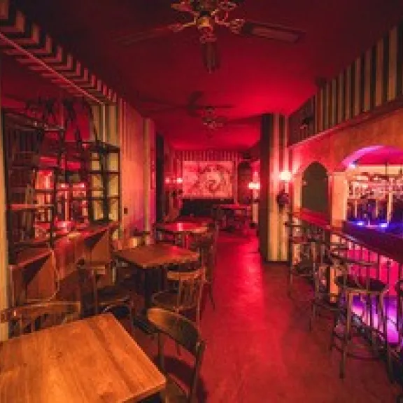 Gemütliche Bar mit Holztischen, gedämpftem roten Licht und gestreiften Wänden