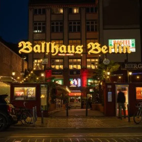 Leuchtendes Ballhaus Berlin bei Nacht, umgeben von Lichtern und Fahrrädern.