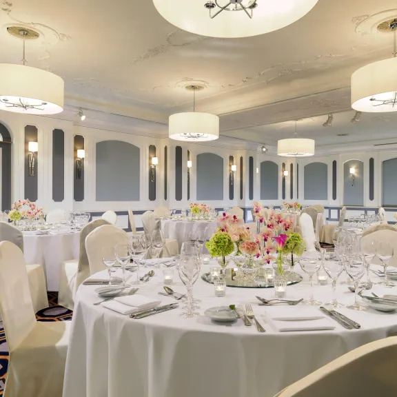 Elegant gedeckter Festsaal mit runden Tischen und Blumenarrangements