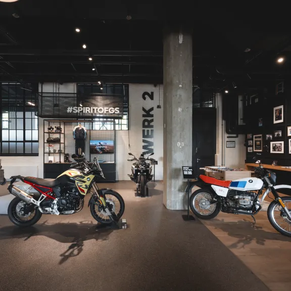 Ausstellungsraum mit mehreren Motorrädern und gerahmten Bildern an den Wänden.