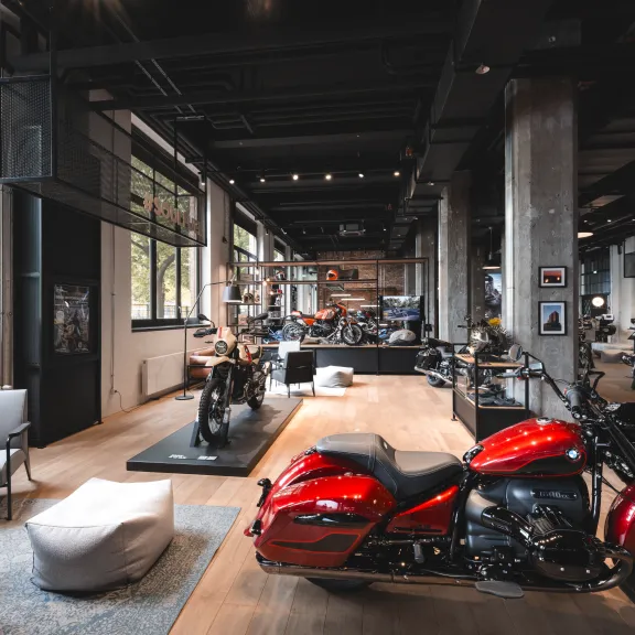 Rotes Motorrad in modernem Ausstellungsraum mit großen Fenstern und Sitzgelegenheiten.