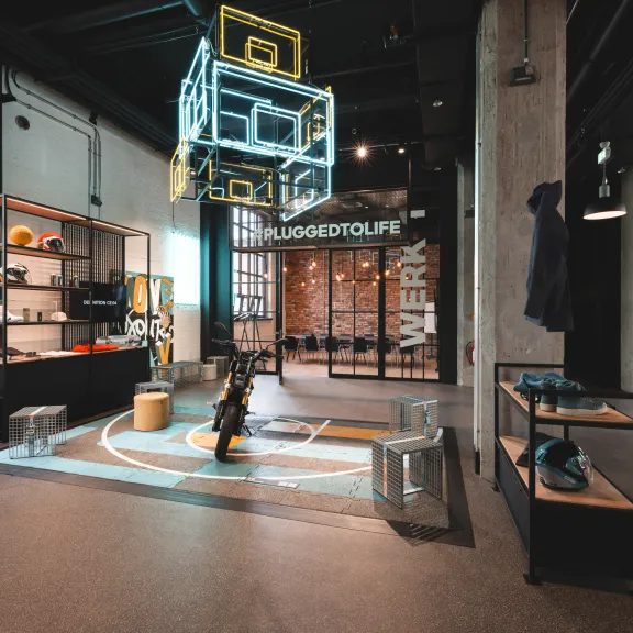 Modernes, offenes Ladenlokal mit Regalen, Sitzgelegenheiten und leuchtenden Dekoelementen.