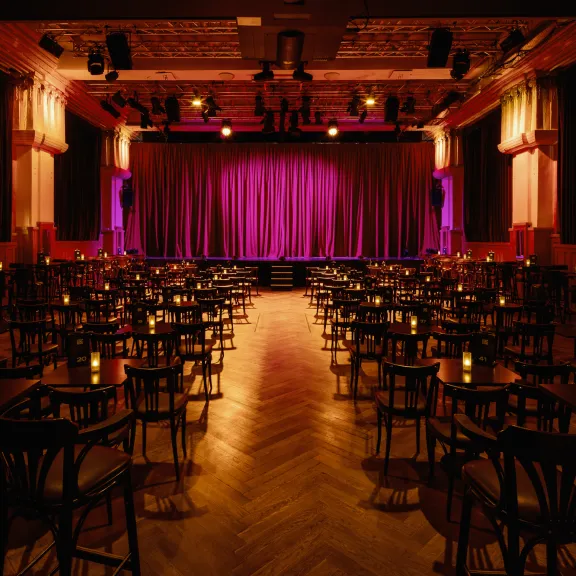 Blick durch den bestuhlten Saal auf die Bühne des Chamäleon Theaters