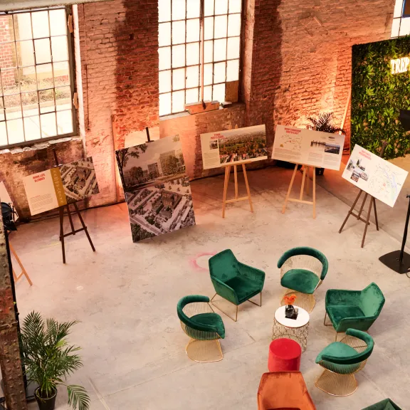 Industrieller Raum mit grünen Sesseln, Tischen und Staffeleien an Backsteinwänden