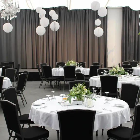 Festlich gedeckter Saal der Forum Factory Berlin mit runden Tischen, weißen Tischdecken und Blumenarrangements.