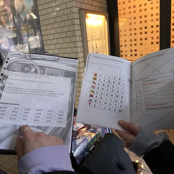 Zwei Personen halten Broschüren mit Tabellen und Symbolen nebeneinander in den Händen.