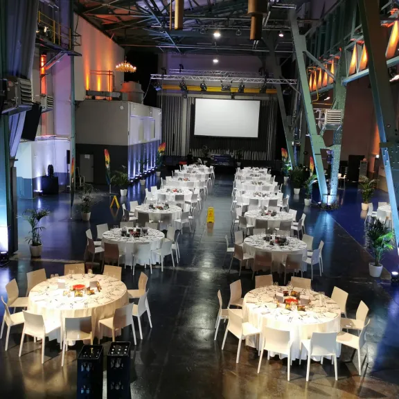 viele Rundtische mit Stühlen in einer Halle