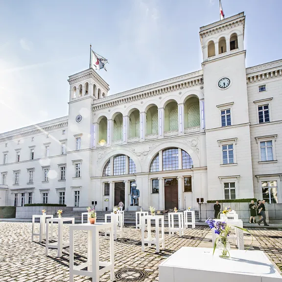 Helles Schlossgebäude mit Türmen, Sonnenschein und weißen Tischen im Innenhof