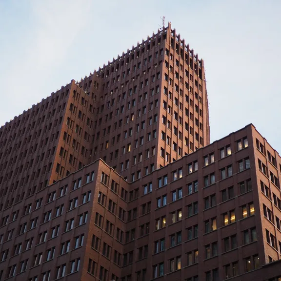 Hoher brauner Bürogebäude mit vielen Fenstern vor blauem Himmel.