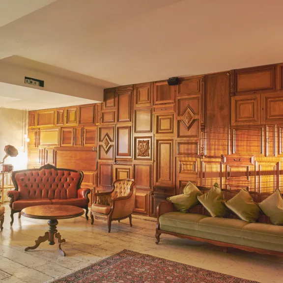 Mit liebevoll ausgewählten Möbelstücken, einer Wandverkleidung aus recycelten Holzpaneelen und einem großen Bücherregal bietet der Whiskey Room eine gemütliche und ausgefallene Atmosphäre.