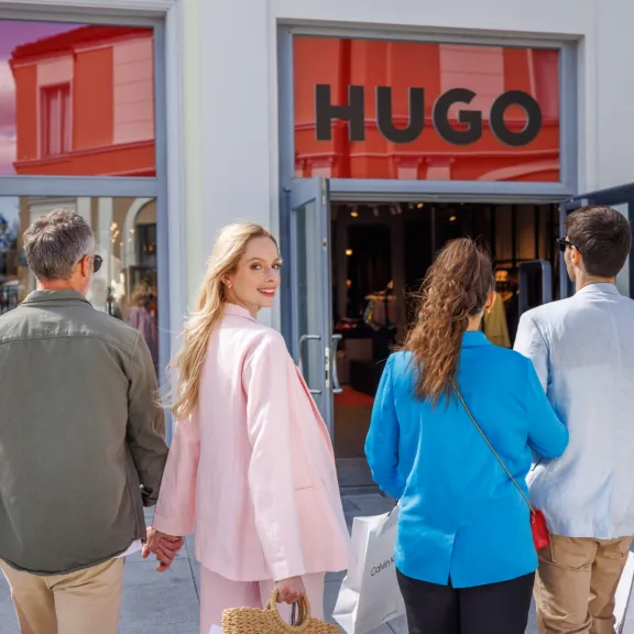 Vier Personen mit Einkaufstaschen vor dem HUGO-Geschäft.