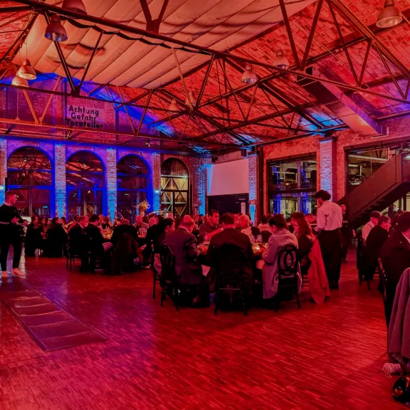 eine große Gruppe sitzt an mehreren Rundtischen gemeinsam in der classic remise