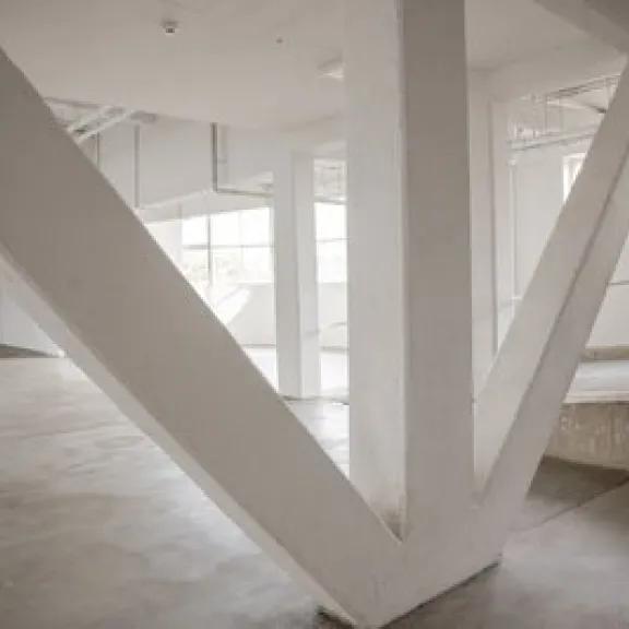 Leerer, heller Raum mit großen weißen Trägern und Fenstern