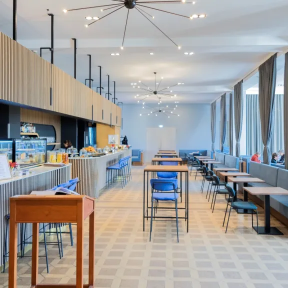 Helles, modernes Café mit blauen Stühlen und großen Fenstern