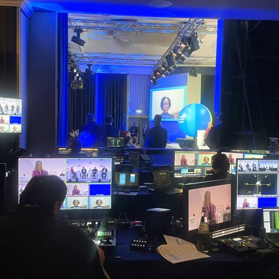 Regieraum mit mehreren Monitoren, Kameras und Menschen bei einer Live-Produktion