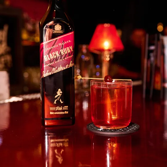 Whiskyflasche und Cocktailglas auf einer Bar vor roter Lampe