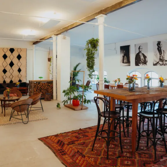 Helles Loft mit Holztisch, Stühlen, Sofas, Pflanzen und Teppichen, modern eingerichtet.