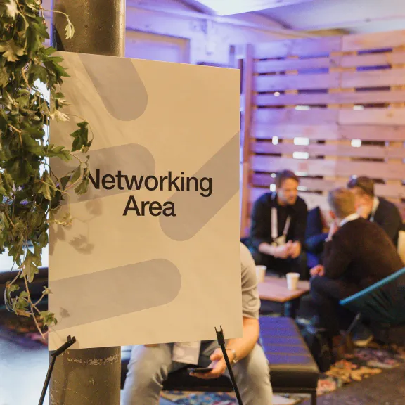 Schild mit "Networking Area", im Hintergrund unterhalten sich mehrere Personen.