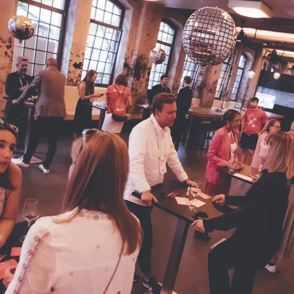 Menschen unterhalten sich in lockerer Atmosphäre in einem modernen Veranstaltungsraum.