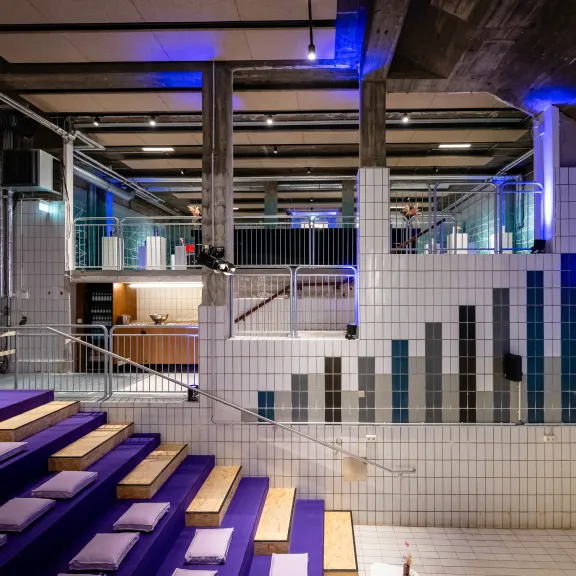 Modernes, industrielles Auditorium mit lila Sitzkissen und gefliestem Treppenaufgang.