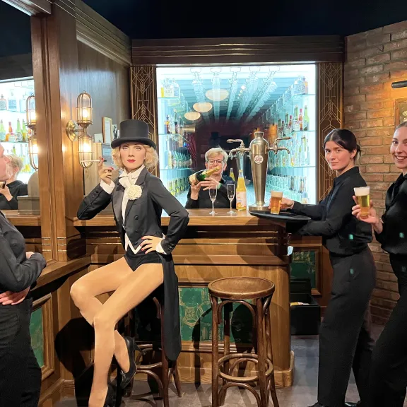 Vier Servicekräfte bei einem Event bei Madame Tussauds mit einer Figur von Marlene Dietrich.
