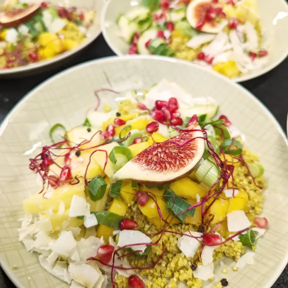 Bunter Salatteller mit Quinoa, Mango, Granatapfel, Feige, Kokos und Kräutern.