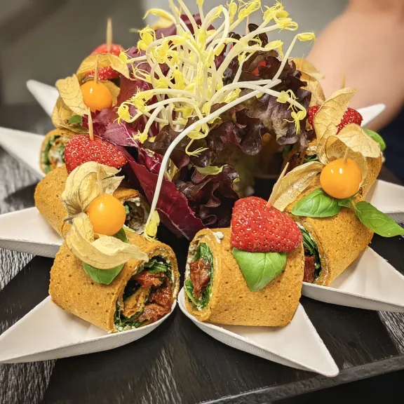 vegane Crepes-Röllchen mit getrockneten Tomaten und Spinat arrangiert als Fingerfood.