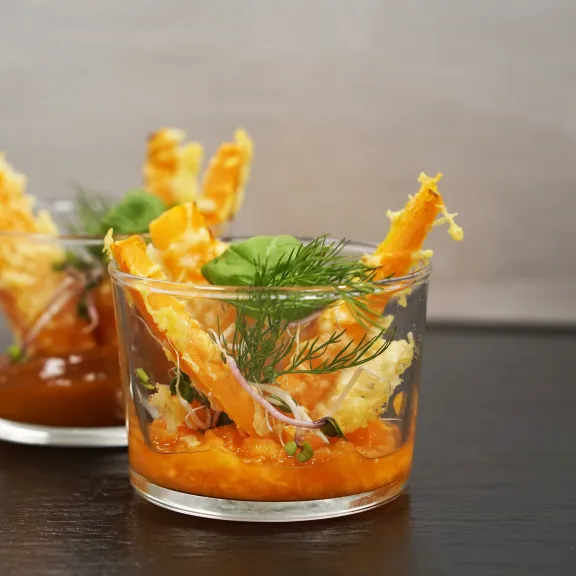 Zwei Gläser mit buntem Gemüse, Kräutern und Grissini auf dunklem Tisch.