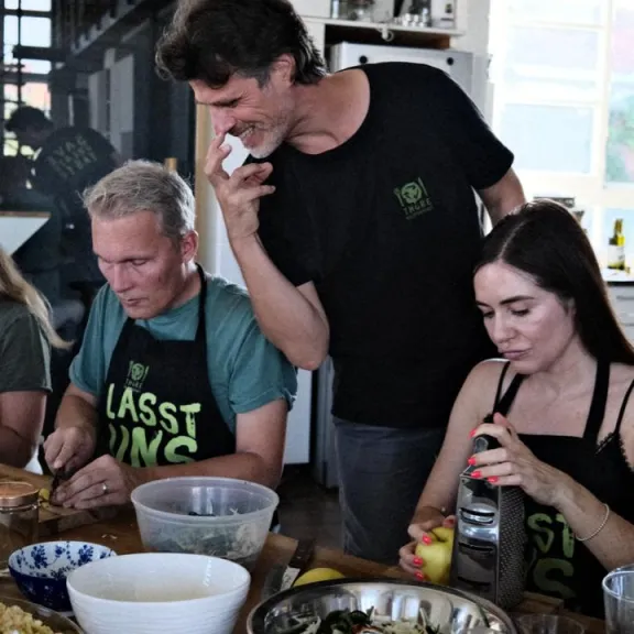 Mehrere Personen bereiten gemeinsam Essen in einer hellen Küche zu.