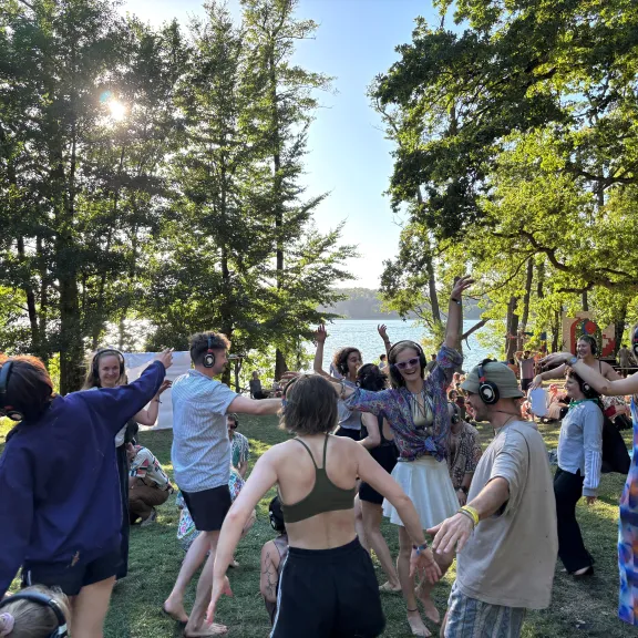 Gruppe von Teilnehmenden mit Kopfhörern bewegt sich im Kreis im Freien bei einem interaktiven Ohrenzirkus-Format.