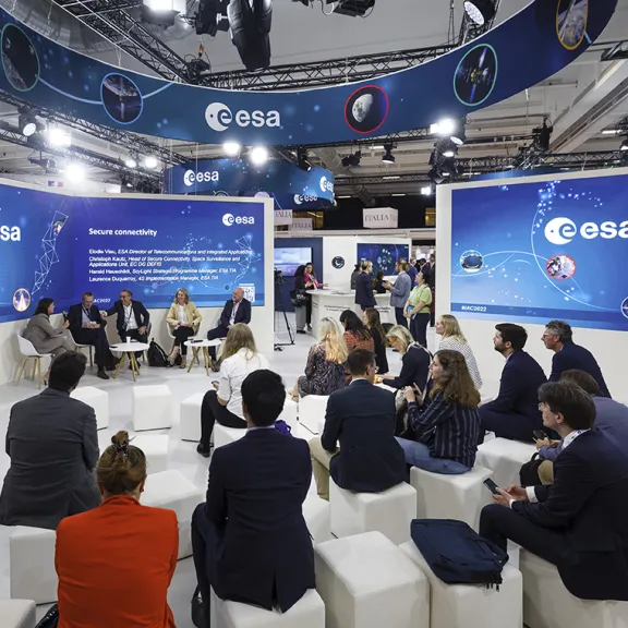 Menschen sitzen im Kreis bei einer Diskussionsrunde auf einer Messe der ESA.