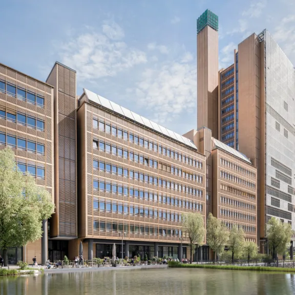Modernes Bürogebäude aus Backstein mit Teich im Vordergrund und blauem Himmel