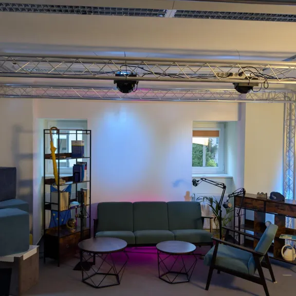 Modernes Wohnzimmer mit Sofa, Sesseln, Regalen und Beleuchtung, gemütlich eingerichtet.