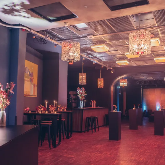 Stilvoll dekorierter Festsaal mit Kronleuchtern, Stehtischen und Blumenarrangements.