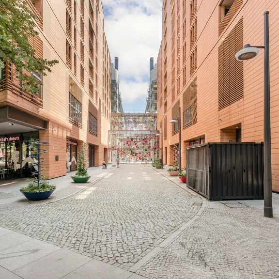 Moderner Innenhof mit orangefarbenen Gebäuden und gepflastertem Weg bei Tageslicht.