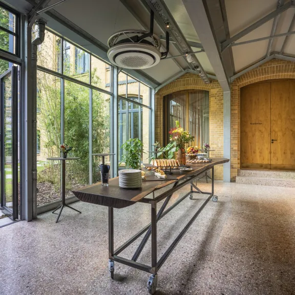 Moderner Innenraum mit großem Holztor, Glastüren und gedecktem Tisch, Gartenblick.