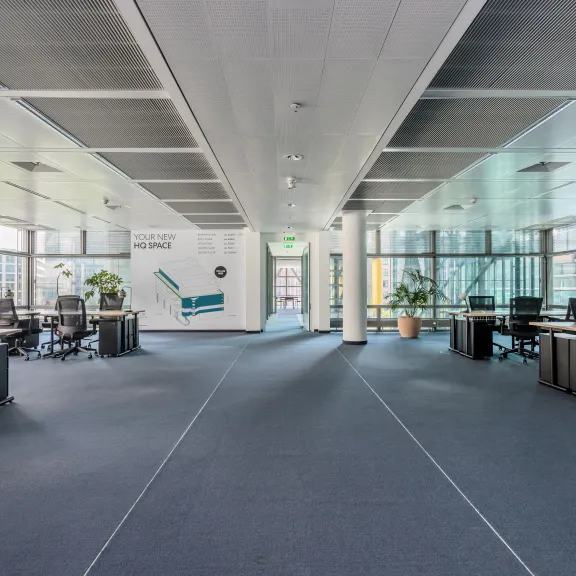 Modernes, leeres Großraumbüro mit Schreibtischen und großen Fenstern