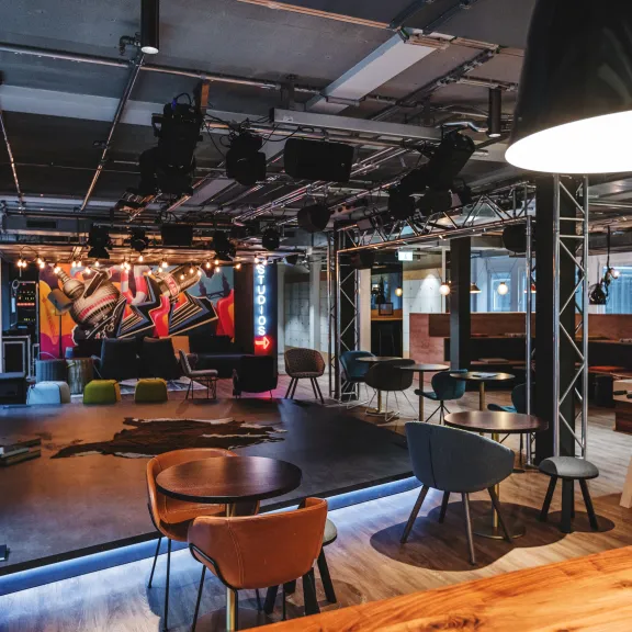 Moderner Veranstaltungsraum mit Bühne, buntem Graffiti und Sitzbereichen.