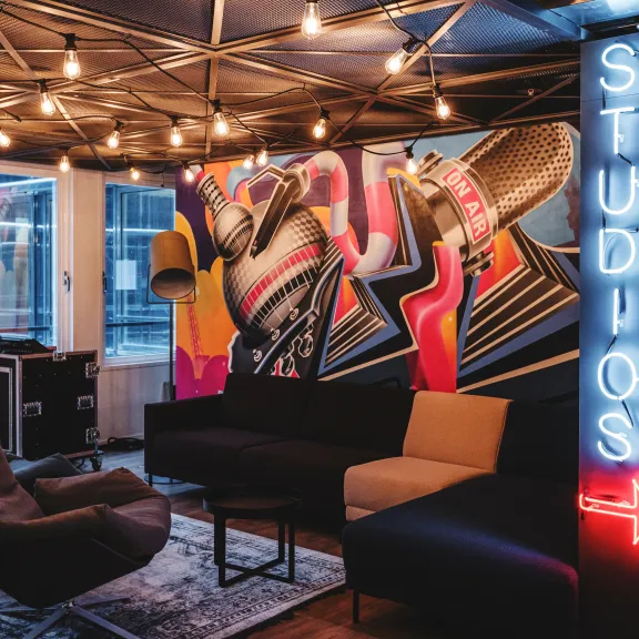 Modern eingerichtete Lounge mit buntem Wandgemälde und leuchtendem Neonschild.