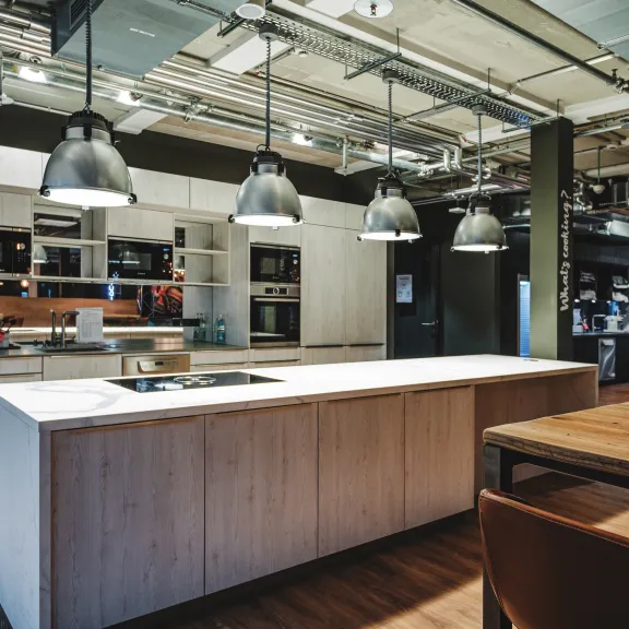 Moderner Küchenbereich mit großer Kochinsel, Hängelampen und Holzboden
