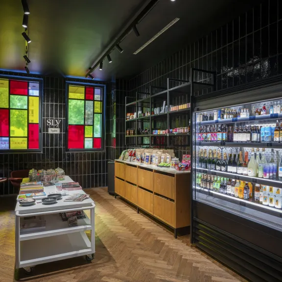 Moderner Kiosk mit beleuchtetem Kühlschrank, buntem Fenster und Holzfußboden.