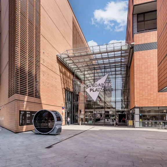 Modernes Gebäude mit Glasfassade, Eingang mit Vitra-Logo bei sonnigem Wetter.