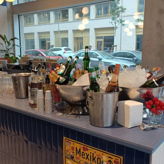 Bar mit Eiswannen und Flaschen, moderne Lampen, Fenster mit Blick nach draußen.