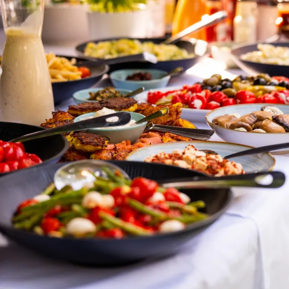 Verschiedene bunte Vorspeisen auf einem Buffet mit Salaten und Gemüse.