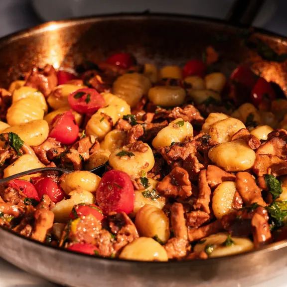 Pfanne mit Gnocchi, Pilzen, Tomaten und frischen Kräutern
