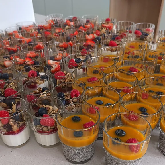 Viele Dessertgläser mit Beeren, Joghurt, Müsli und Chiasamen, bunt angerichtet.