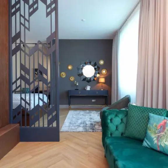 Modernes Wohnzimmer mit grünem Sofa, buntem Kissen, Spiegel und Vorhängen.