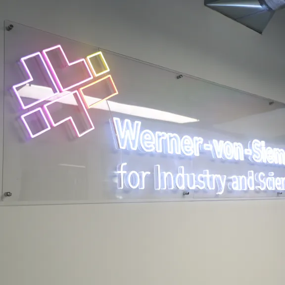 Leuchtendes Logo und Schriftzug "Werner-von-Siemens Centre for Industry and Science" an der Wand.