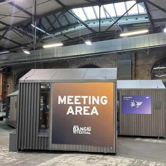 Grauer Meeting-Bereich in einer Industriehalle mit großen Fenstern im Dach
